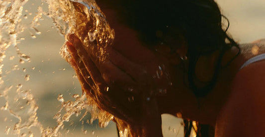 woman splashing water in her face in golden hour