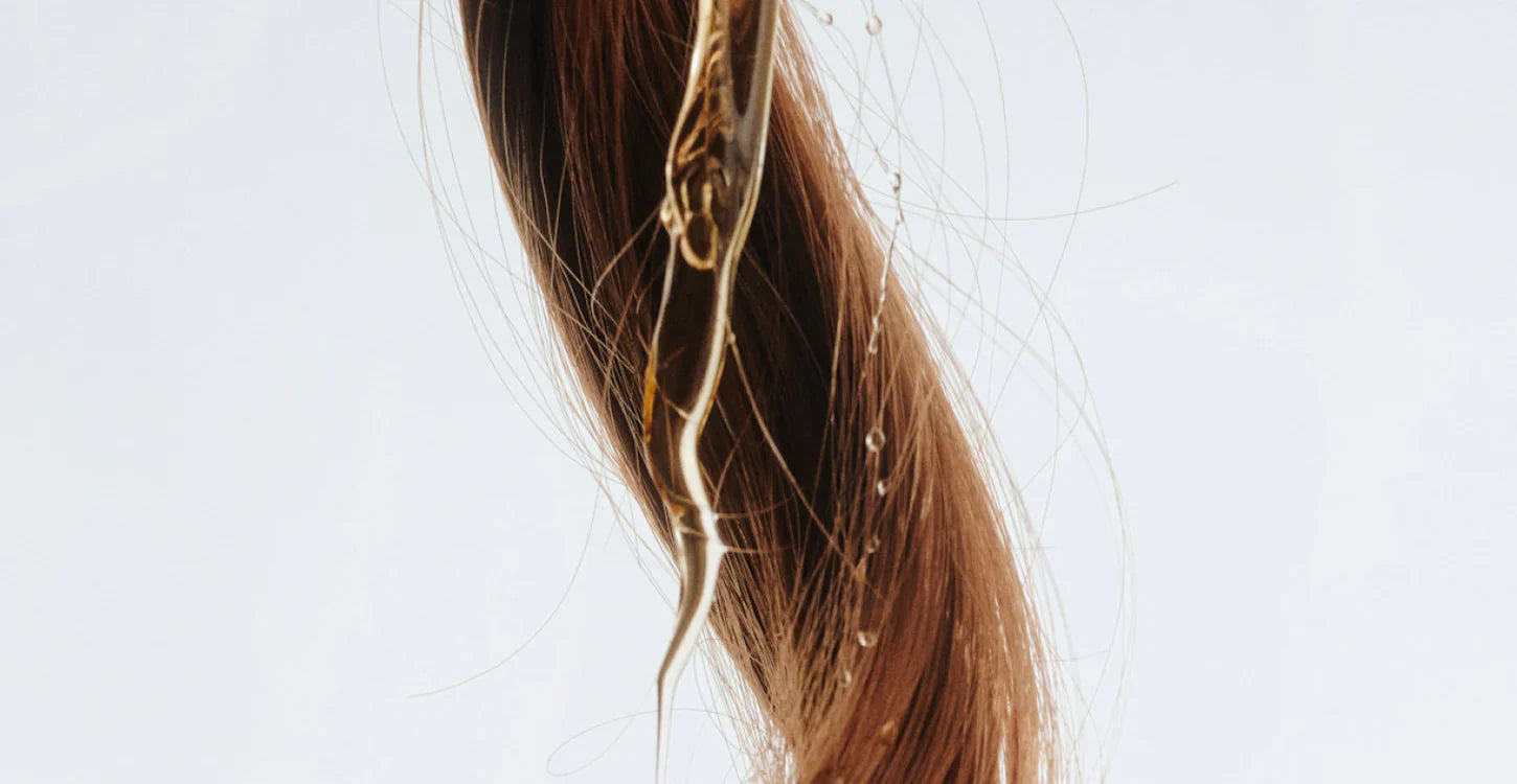 Närbild på hårslinga med produkt som droppar på den