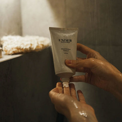 Bild visar en person som applicerar hårmask på handen i duschen.