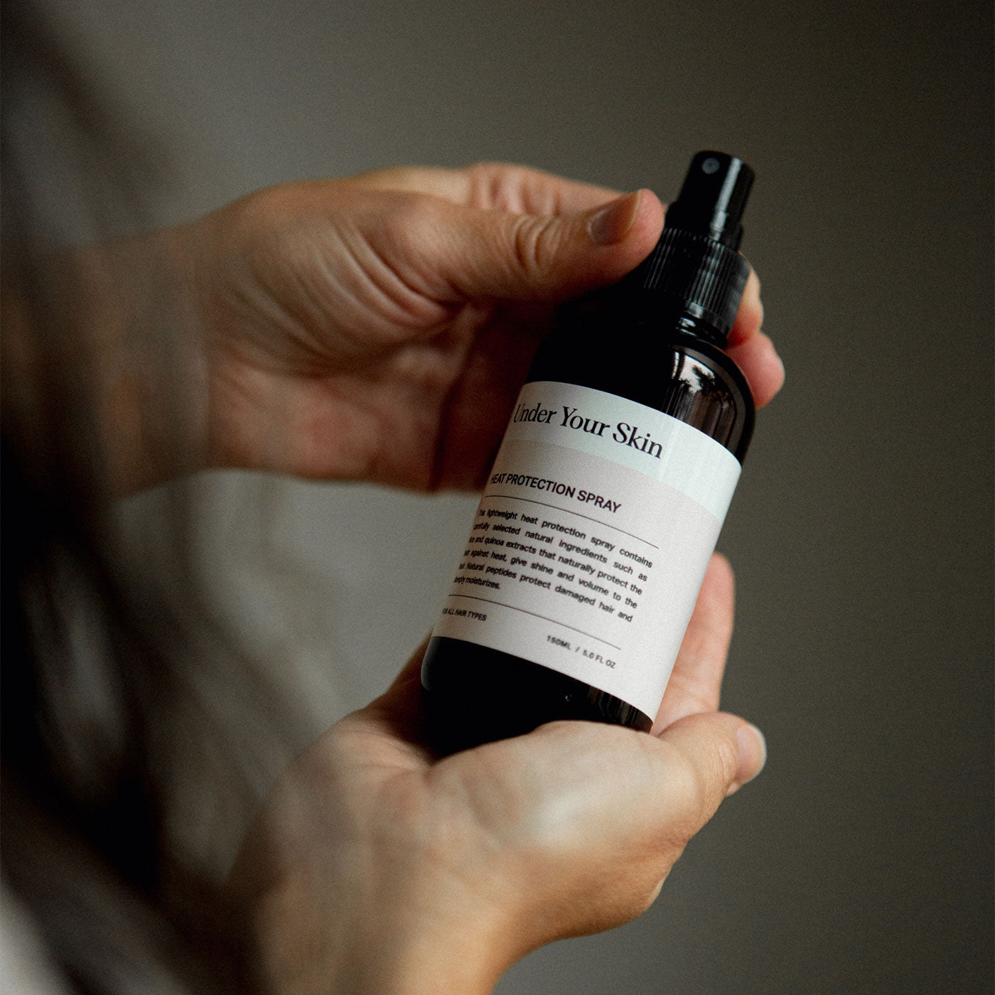 Närbild på värmeskydd för håret i hand, lifestylebild