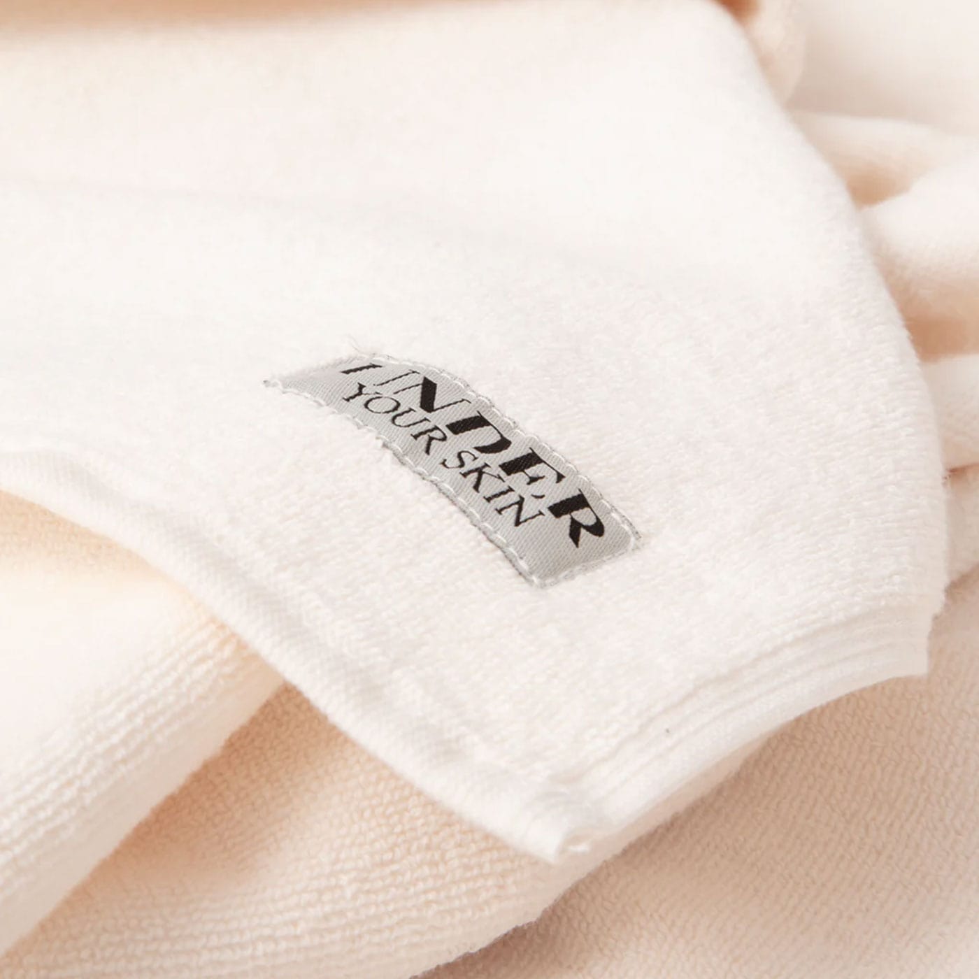 Närbild på UYS-logotypen på rosa handdukar.