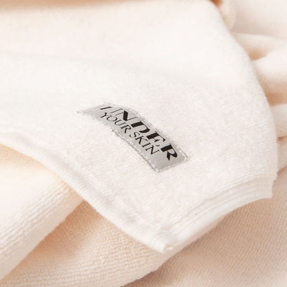 Närbild på UYS-logotypen på rosa handdukar.