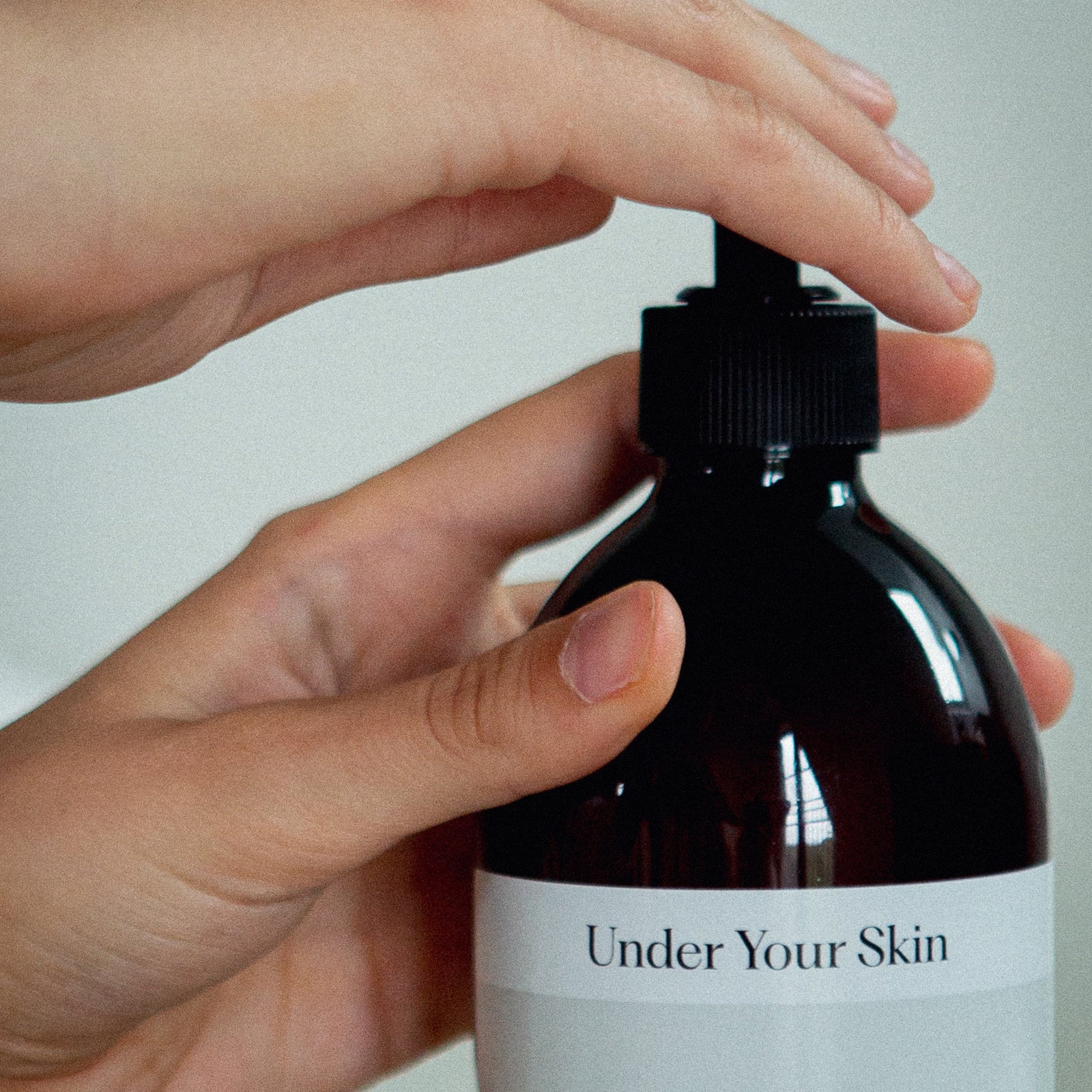 Närbild på body wash-flaska där en hand trycker ner pumpen