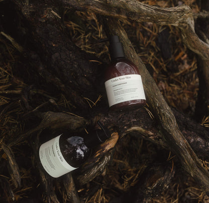 Hårvårdsprodukter placerade på trädrötter i utomhusmiljö.