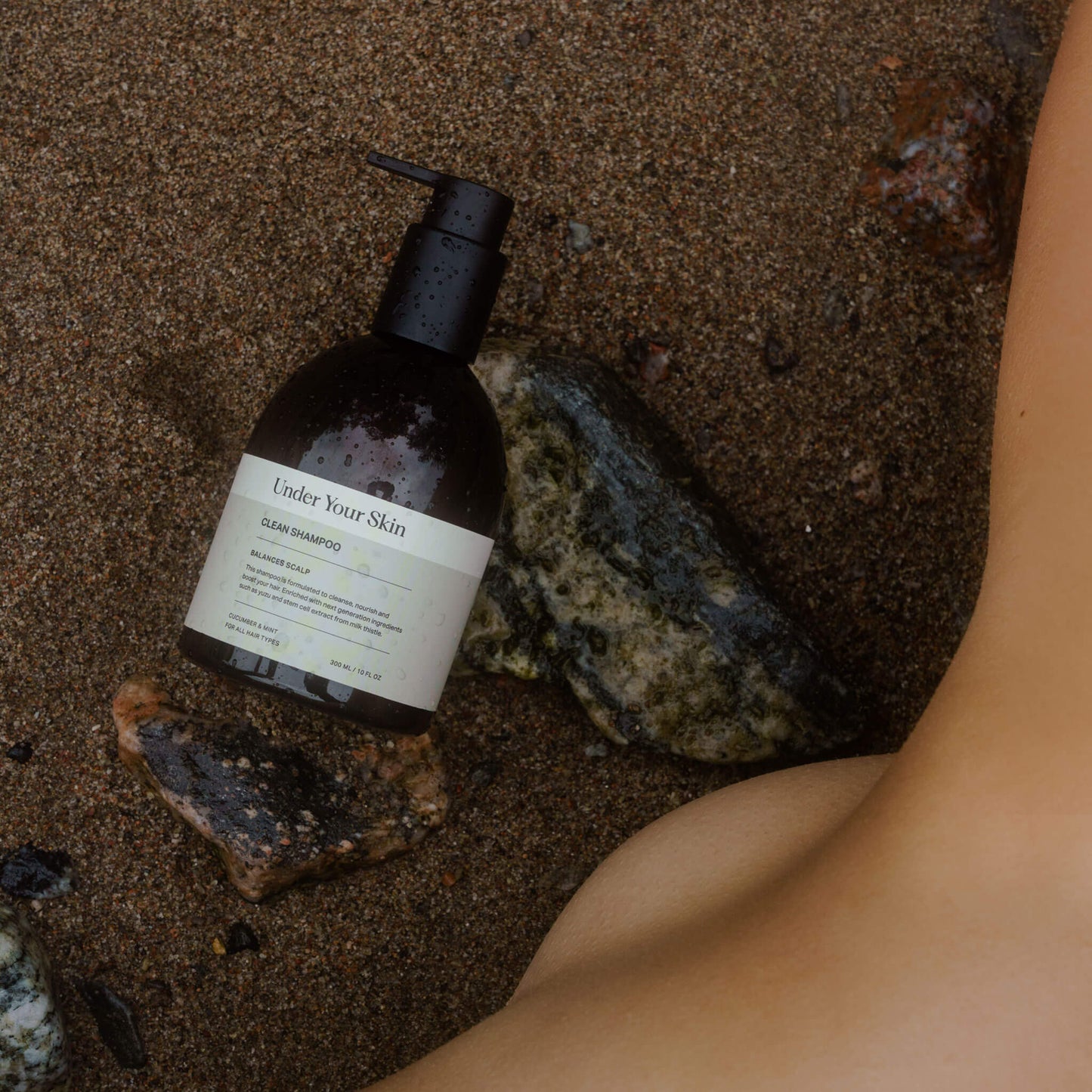 Produkt placerad på sandstrand med stenar intill och en fot bredvid.