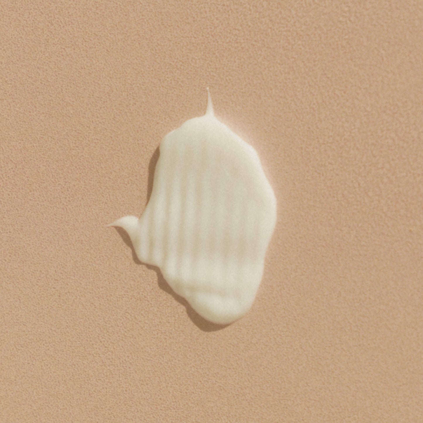 Närbild av en klick balsam på beige texturerad yta.