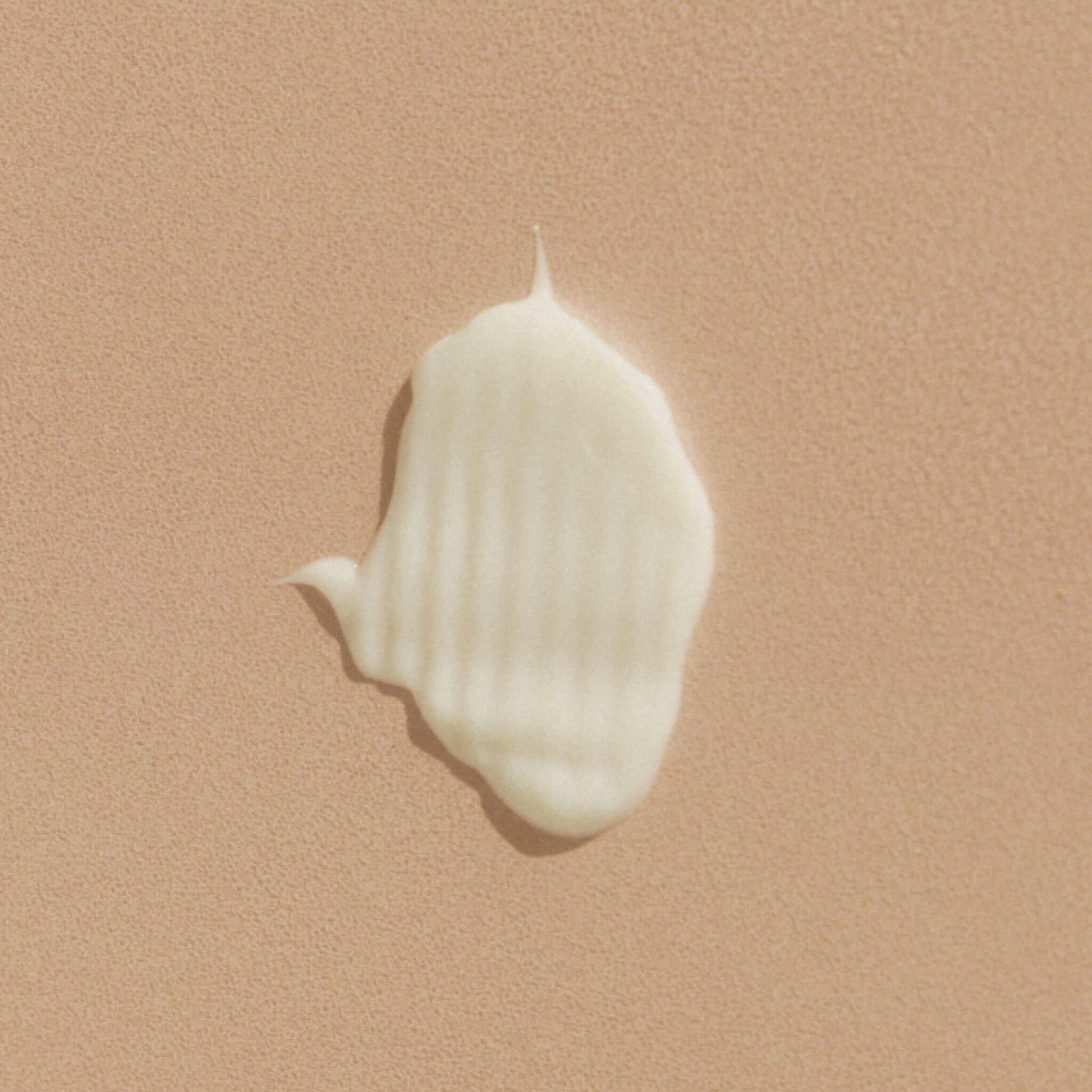 Närbild av en klick balsam på beige texturerad yta.