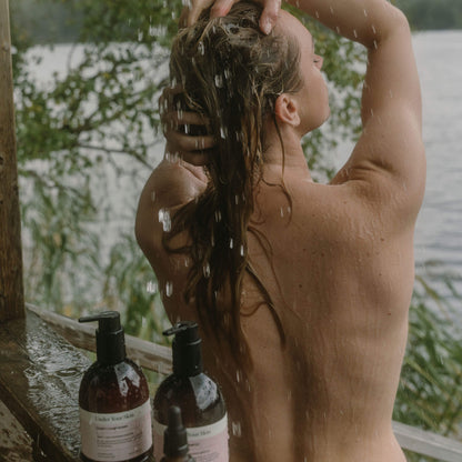 Kvinna som tvättar håret i utomhusmiljö.