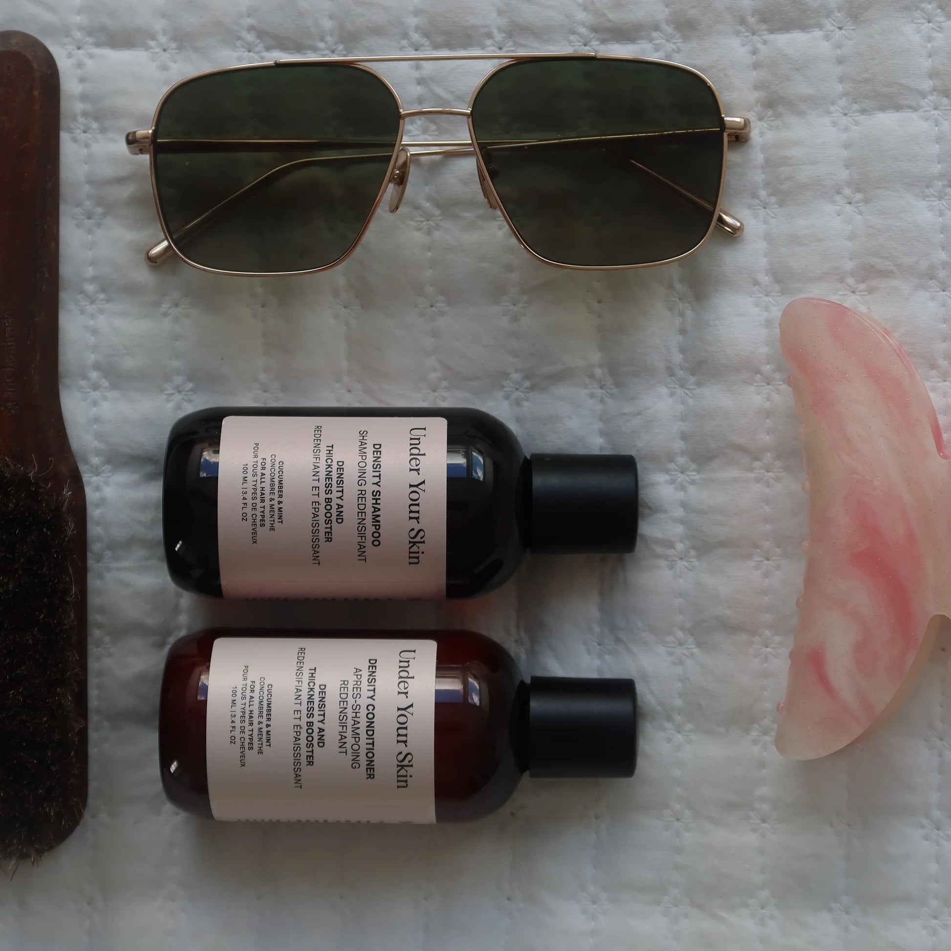 Density Duo på vitt lakan tillsammans med solglasögon, hårklämma och trähårborste