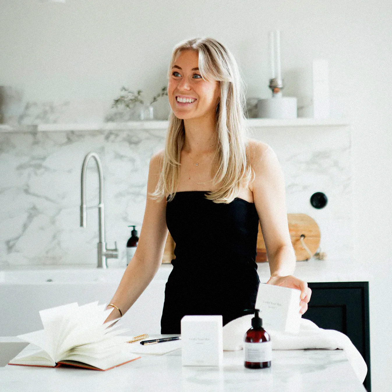 Lovisa i köksmiljö med böcker och produkter på köksbänken.