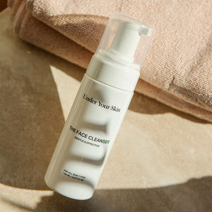 närbild på Face cleanser som lutar mot rosa handdukar i bakgrunden.