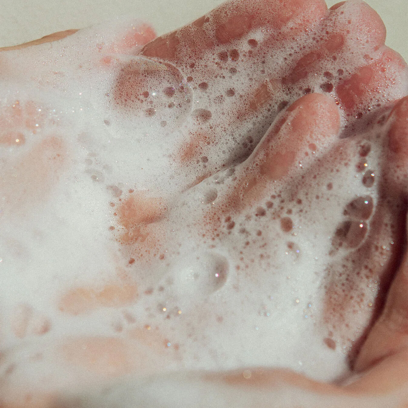 Face cleanser applicerad på händer och utspridd.