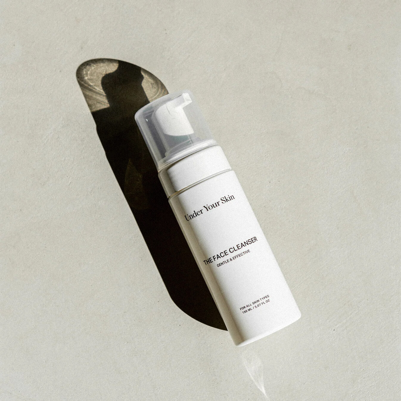 Face cleanser liggandes på en grå yta med en skugga.