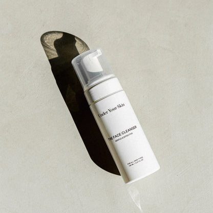 Face cleanser liggandes på en grå yta med en skugga.