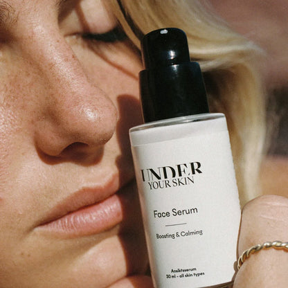 Närbild på ansiktskräm som en kvinna håller nära sitt ansikte.