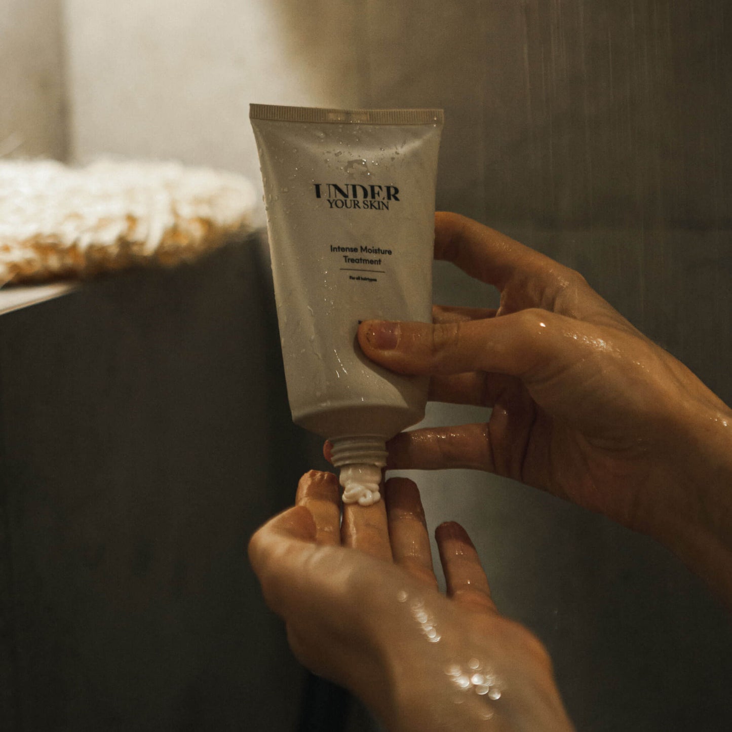 Bild visar en person som applicerar hårmask på handen i duschen.