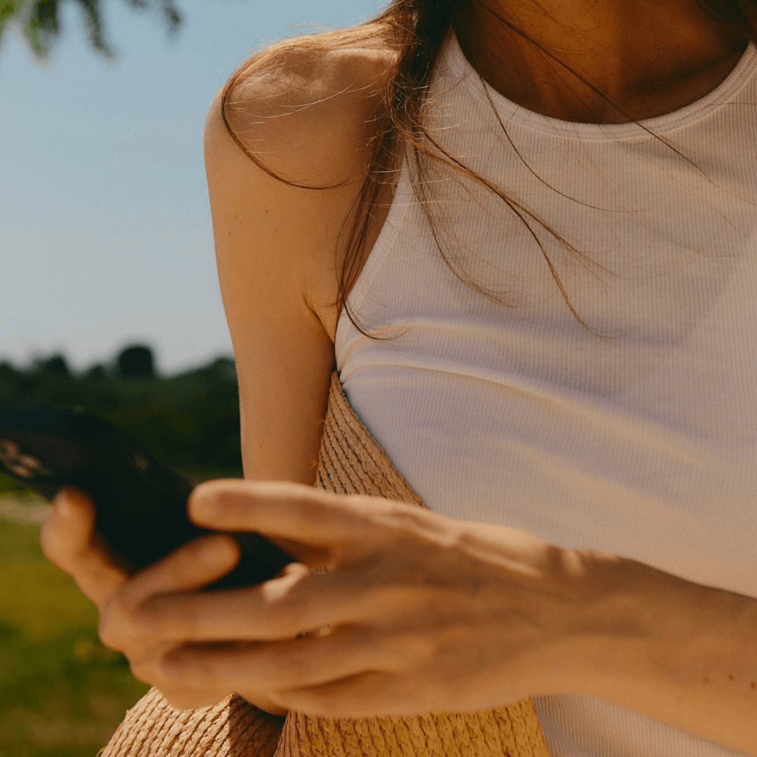 close up of a hands holding a mobile with woman on the background.