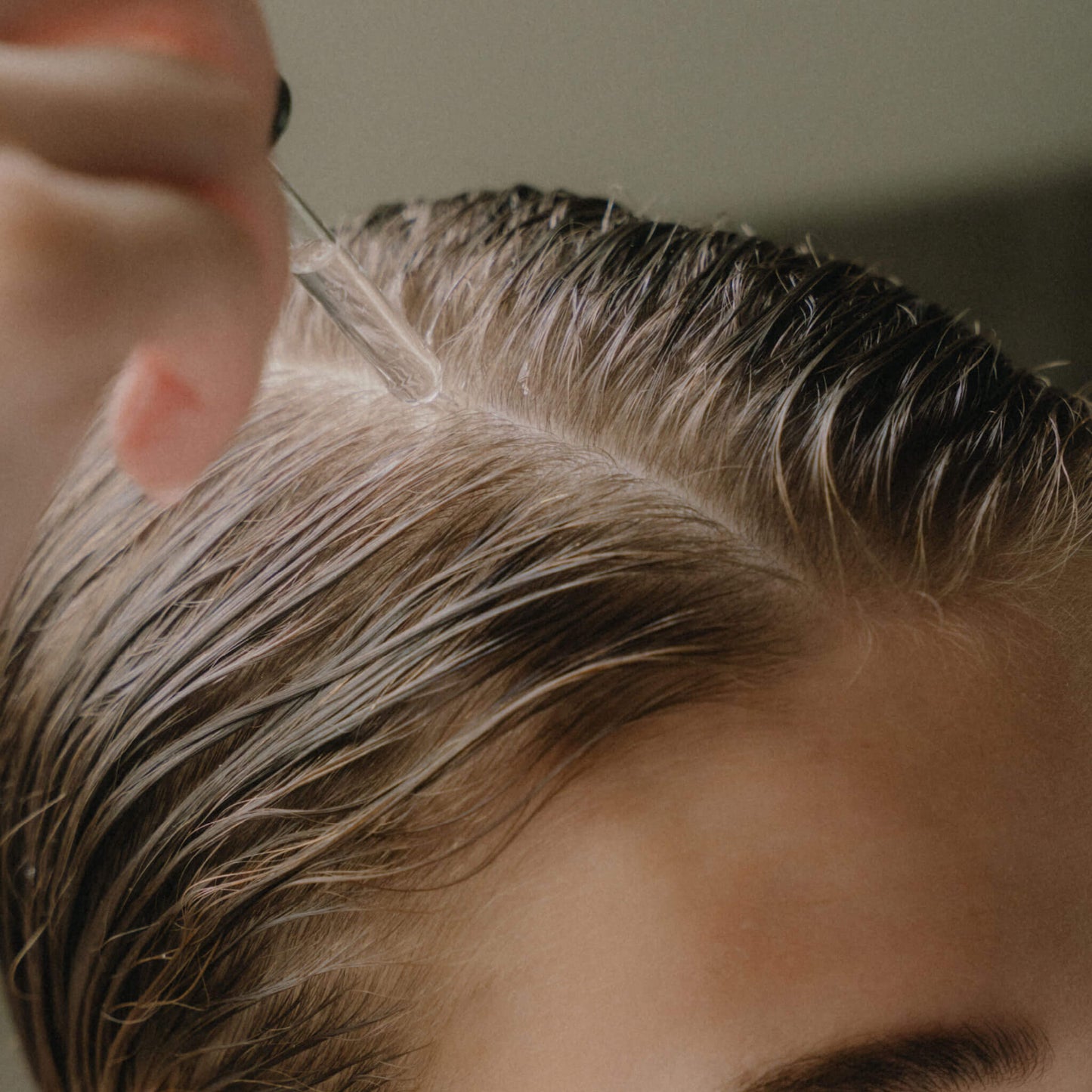 Närbild på applicering av serum i håret.