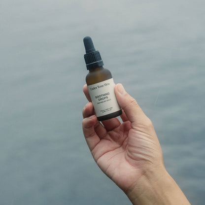 Hand som håller en Soothing Drop-produkt över vatten.