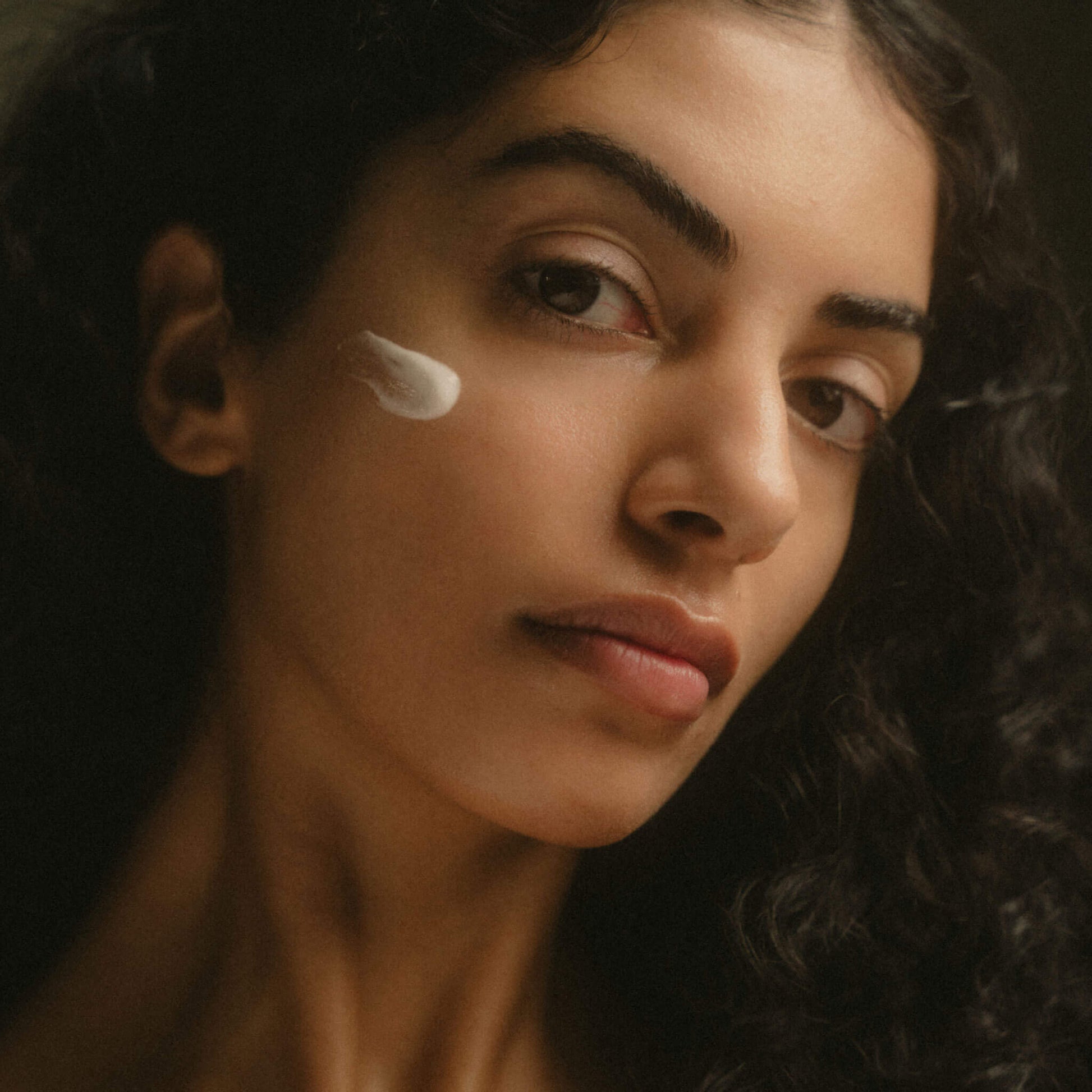 Kvinna som tittar in i kameran med ett serumtest applicerat på kinden.