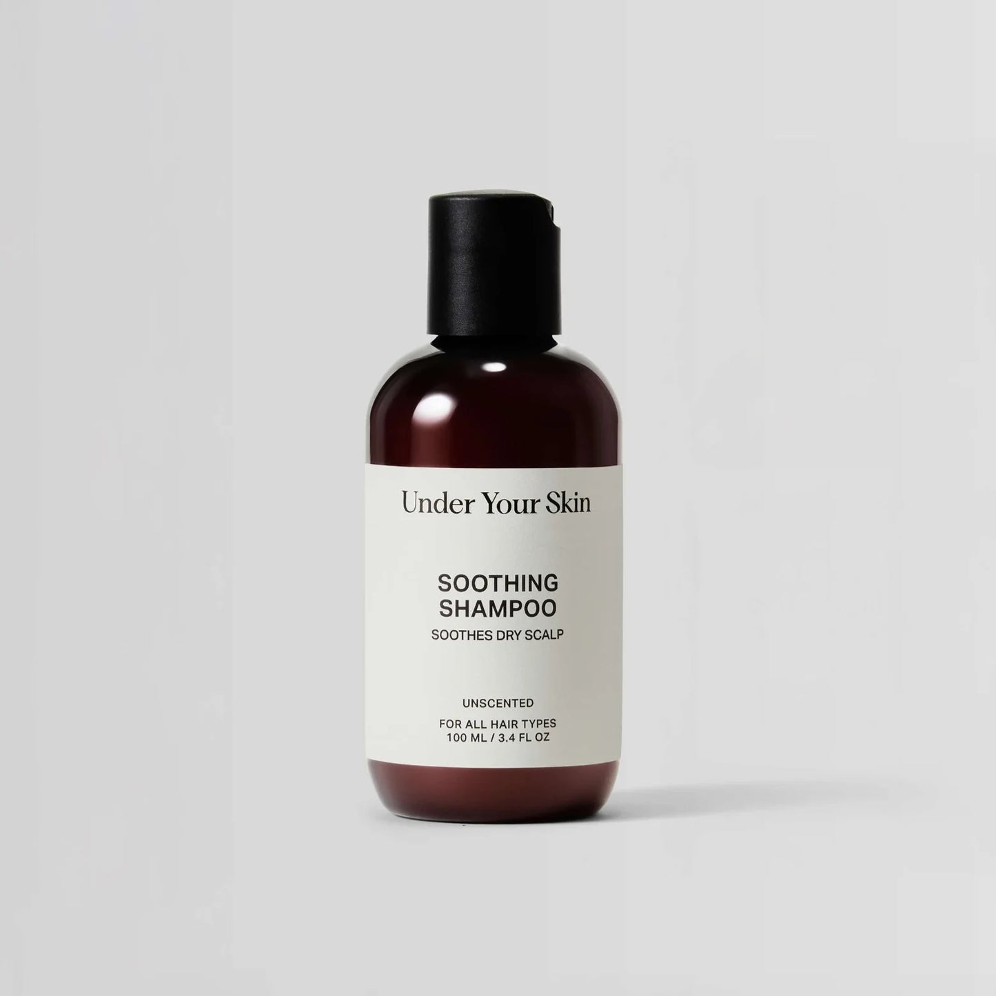 Bottle of 'Under Your Skin' soothing shampoo on a light gray background