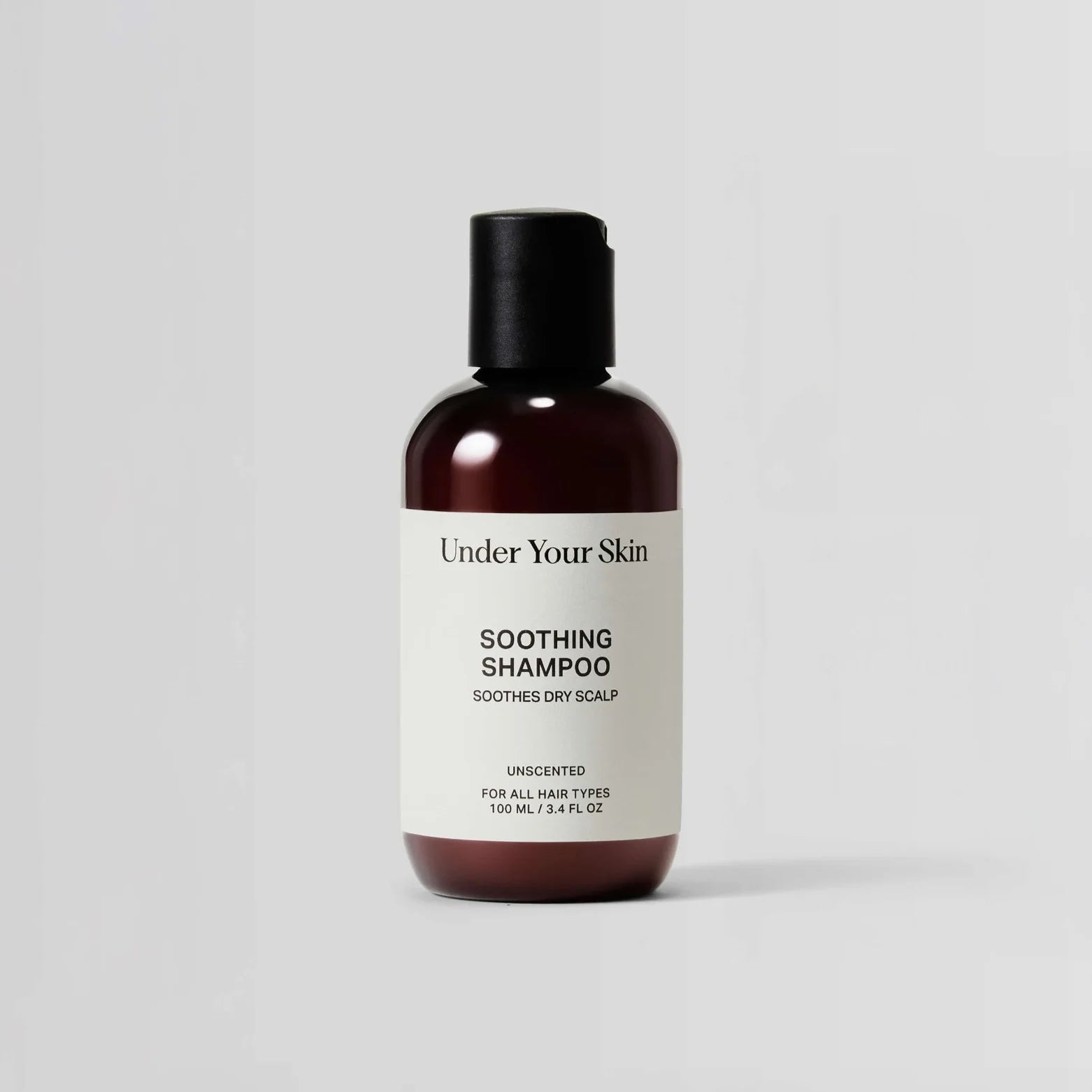 Bottle of 'Under Your Skin' soothing shampoo on a light gray background