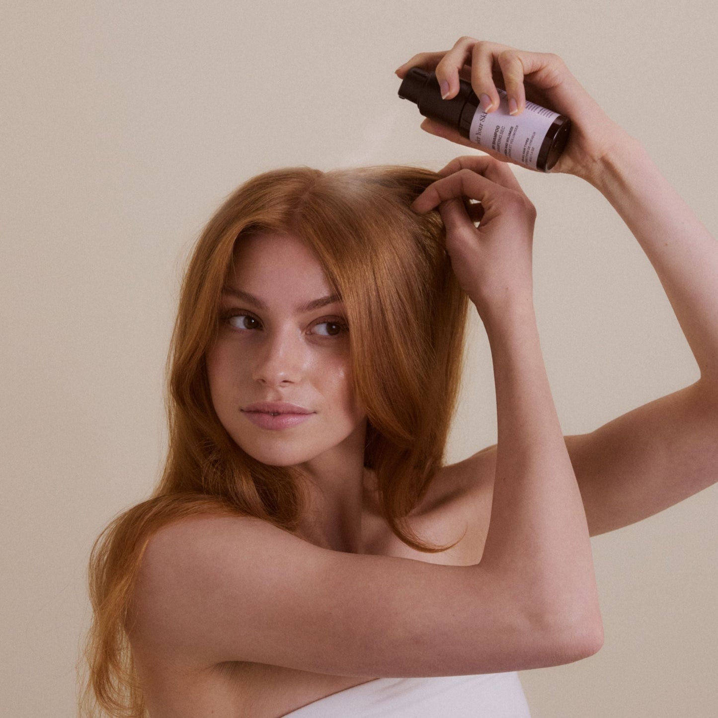 Kvinna sprayar sitt röda hår med torrschampo